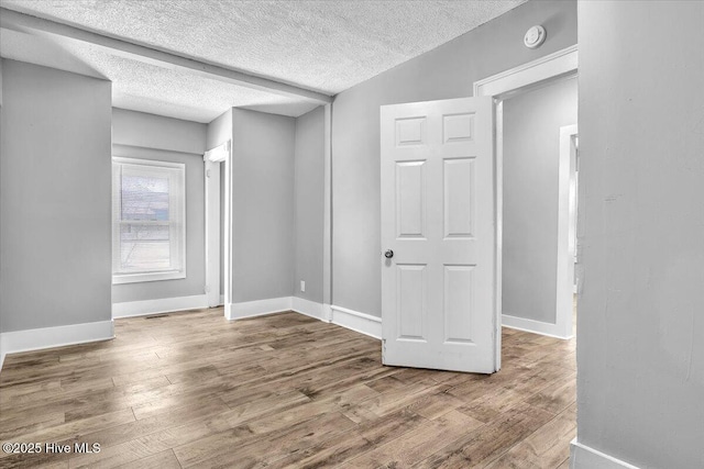 empty room featuring wood-type flooring, lofted ceiling, and a textured ceiling