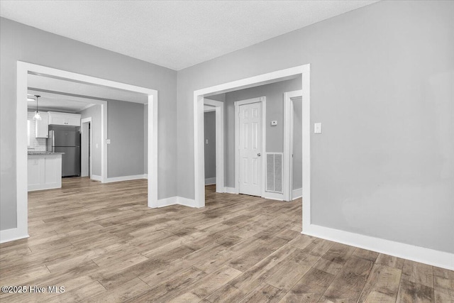 empty room featuring light wood-type flooring and a textured ceiling