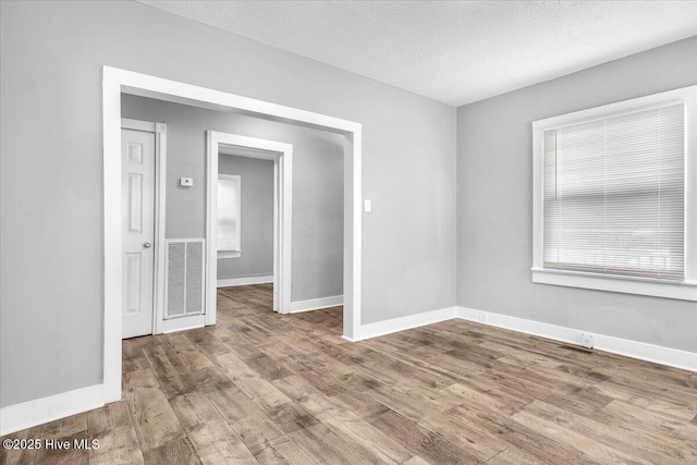 empty room with light hardwood / wood-style floors and a textured ceiling