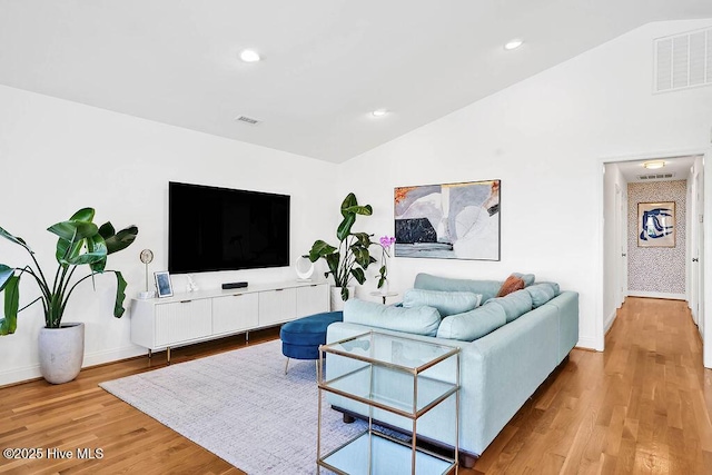 living area with visible vents, lofted ceiling, and light wood finished floors