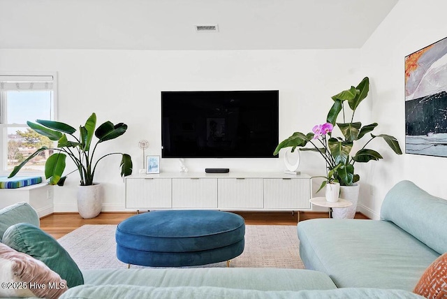 living area with visible vents, baseboards, and wood finished floors