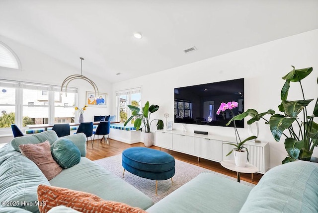 living room with lofted ceiling, wood finished floors, and visible vents