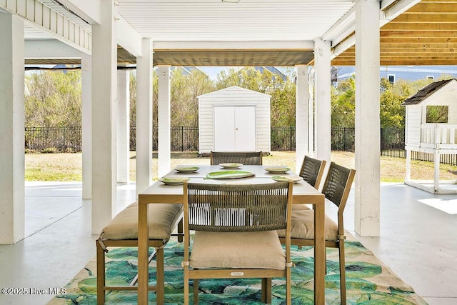 view of patio with an outdoor structure, a storage unit, a fenced backyard, and outdoor dining area