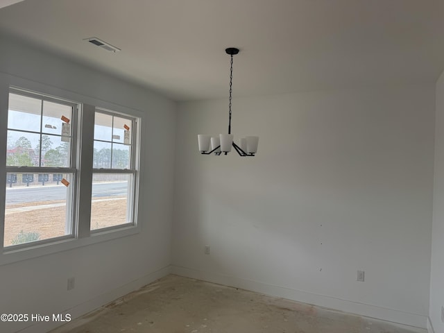 unfurnished dining area featuring concrete flooring and an inviting chandelier