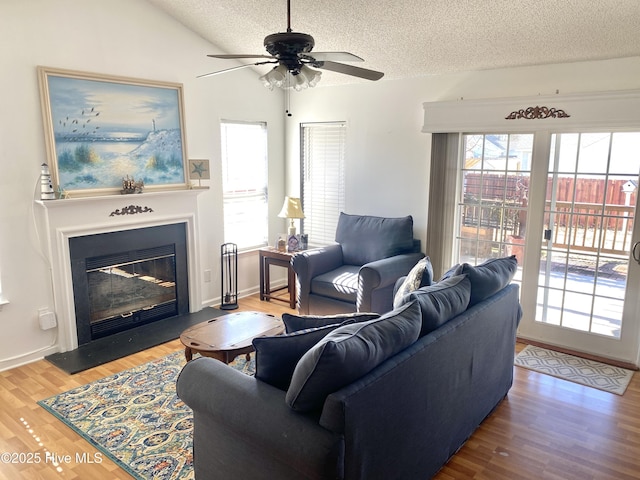 living room featuring wood-type flooring, lofted ceiling, ceiling fan, and a textured ceiling