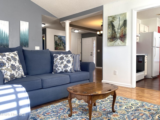 living room featuring hardwood / wood-style flooring, lofted ceiling, a textured ceiling, and decorative columns