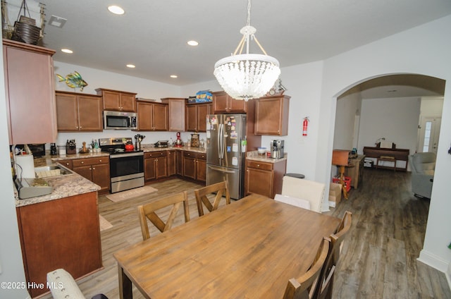 kitchen featuring appliances with stainless steel finishes, decorative light fixtures, wood-type flooring, sink, and a chandelier