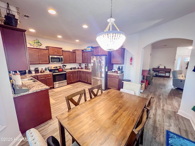 dining room featuring sink, a chandelier, and light wood-type flooring