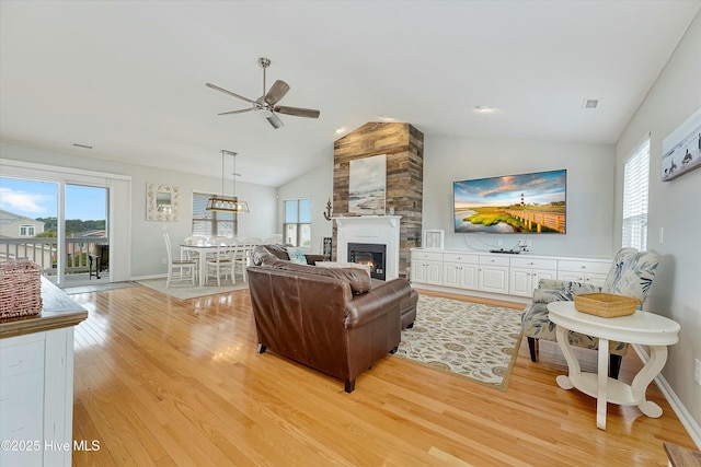 living room featuring ceiling fan, a fireplace, vaulted ceiling, and light hardwood / wood-style flooring