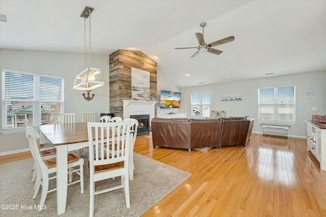 dining area featuring lofted ceiling, a fireplace, a wealth of natural light, and light hardwood / wood-style floors