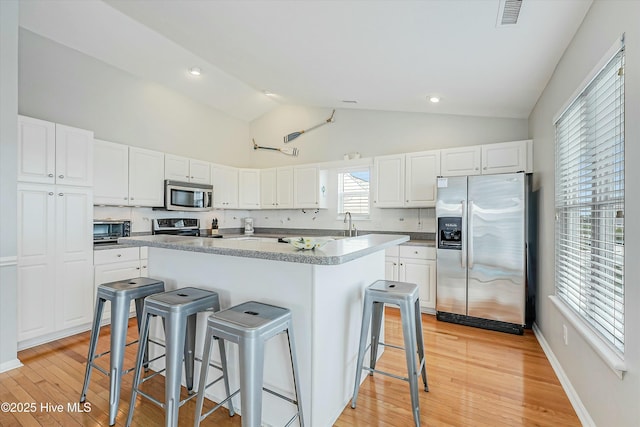 kitchen featuring appliances with stainless steel finishes, a center island, white cabinets, and a kitchen breakfast bar