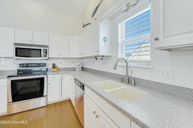 kitchen with stainless steel appliances, sink, white cabinets, and backsplash