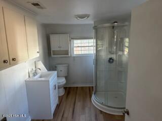 bathroom with wood-type flooring, sink, an enclosed shower, and toilet