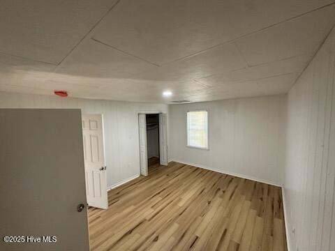 interior space with light wood-type flooring and wood walls