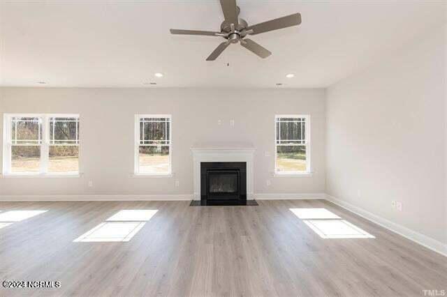 unfurnished living room featuring plenty of natural light, ceiling fan, and light hardwood / wood-style flooring