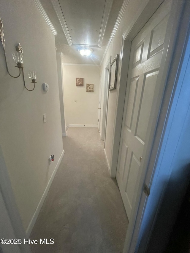 hall featuring attic access, light carpet, baseboards, and crown molding