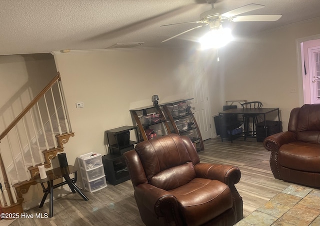 living room featuring hardwood / wood-style flooring, ceiling fan, crown molding, and a textured ceiling