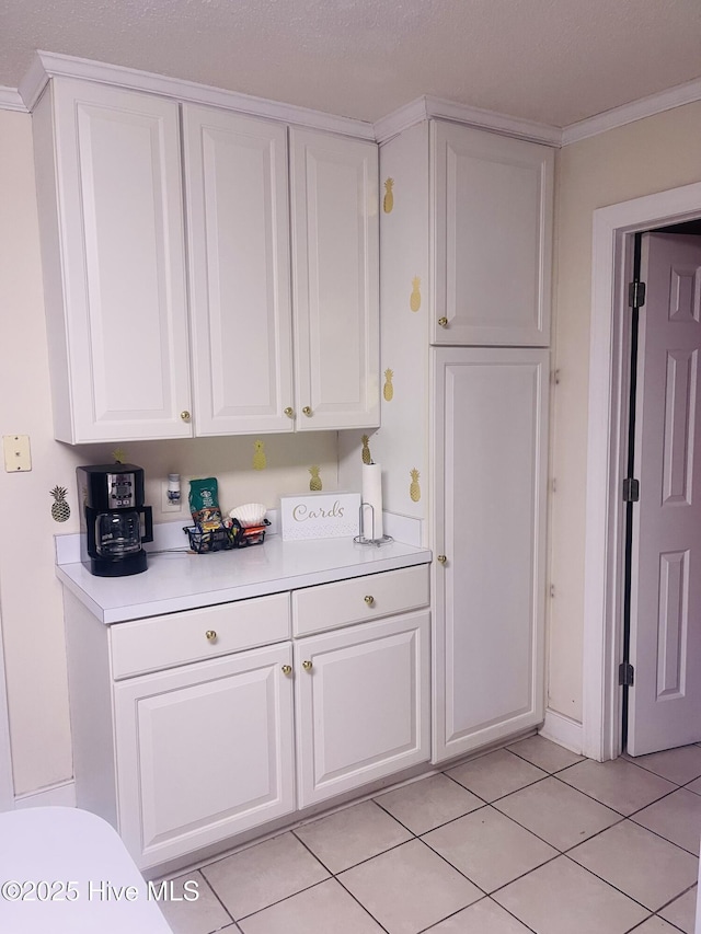 interior space featuring light countertops, white cabinetry, light tile patterned floors, and crown molding