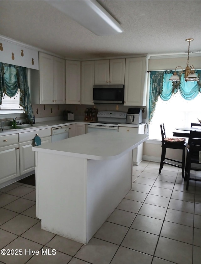 kitchen featuring a sink, a textured ceiling, light tile patterned flooring, white appliances, and light countertops