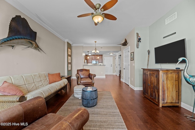 living room featuring dark wood-type flooring, crown molding, and ceiling fan with notable chandelier