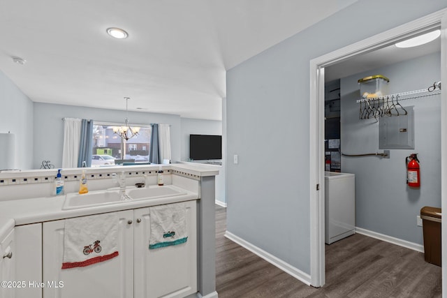 kitchen with pendant lighting, washer / clothes dryer, sink, dark hardwood / wood-style flooring, and electric panel