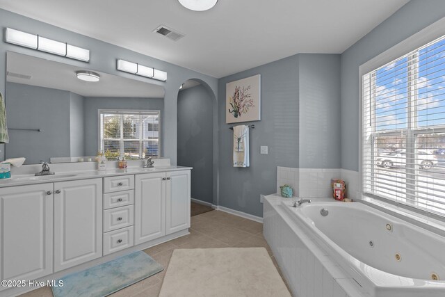 bathroom featuring tile patterned flooring, vanity, and tiled bath