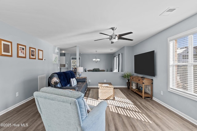 living room with hardwood / wood-style flooring and ceiling fan with notable chandelier