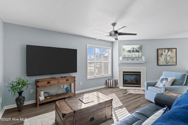 living room featuring a tiled fireplace, hardwood / wood-style flooring, and ceiling fan