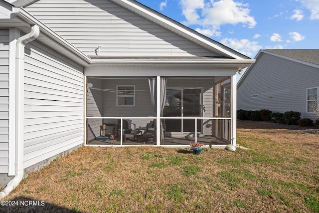 rear view of house with a lawn and a sunroom