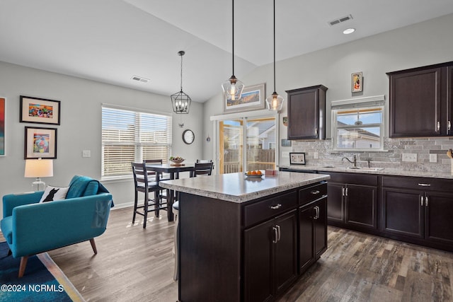 kitchen with a kitchen island, sink, pendant lighting, and dark brown cabinets