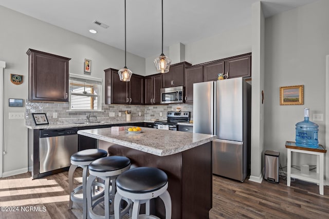 kitchen featuring sink, decorative light fixtures, a kitchen island, stainless steel appliances, and decorative backsplash