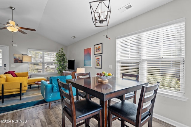 dining room featuring hardwood / wood-style flooring, lofted ceiling, and ceiling fan with notable chandelier