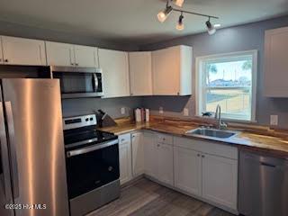 kitchen featuring wood-type flooring, appliances with stainless steel finishes, sink, and white cabinets