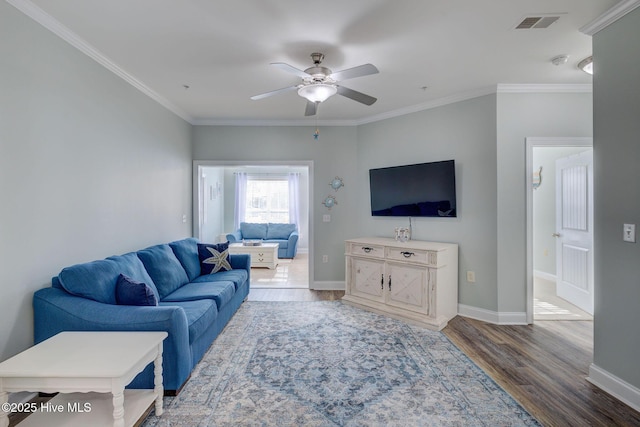 living room with ornamental molding, baseboards, and wood finished floors