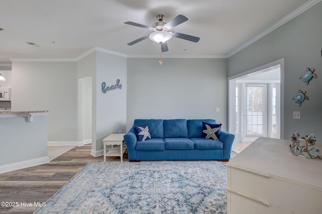 living area featuring crown molding, visible vents, a ceiling fan, wood finished floors, and baseboards