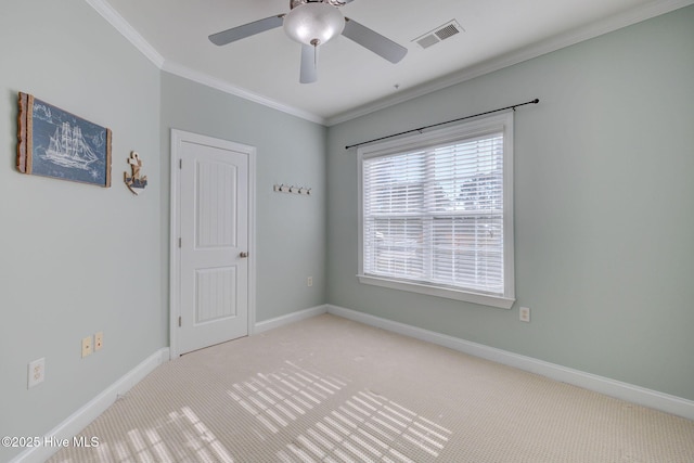 spare room featuring baseboards, visible vents, light colored carpet, ceiling fan, and ornamental molding