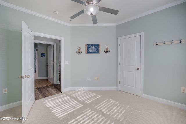 unfurnished bedroom with ornamental molding, carpet, baseboards, and a ceiling fan