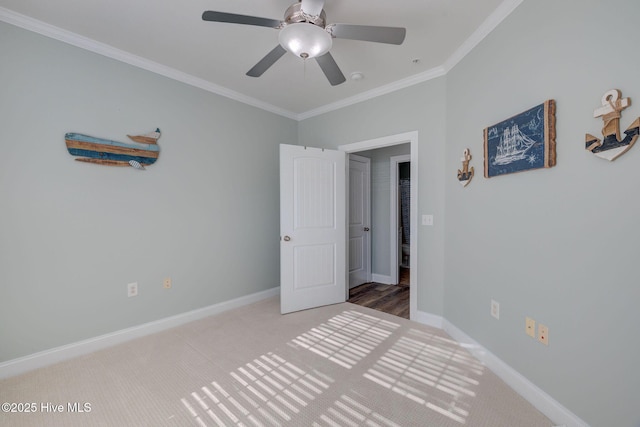 unfurnished bedroom featuring crown molding, ceiling fan, carpet, and baseboards