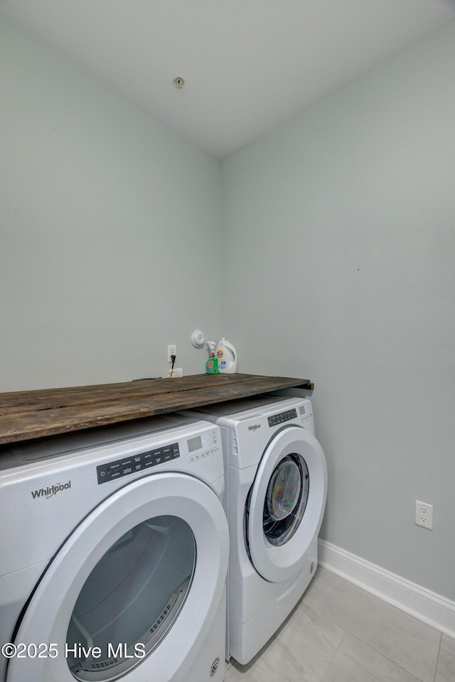 laundry area featuring light tile patterned floors, laundry area, washer and clothes dryer, and baseboards