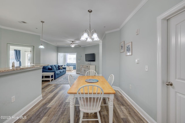 dining room featuring baseboards, visible vents, dark wood-style flooring, crown molding, and ceiling fan with notable chandelier