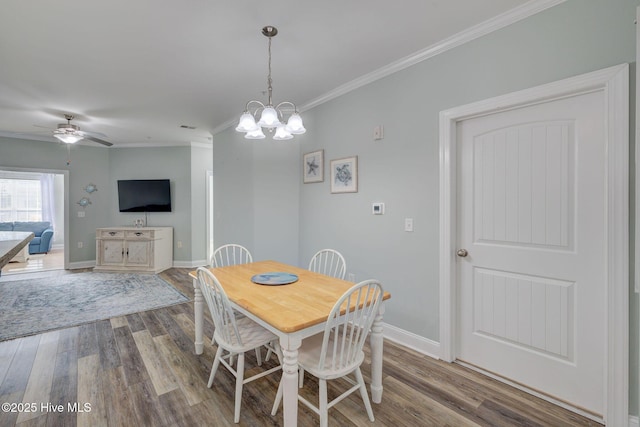 dining area featuring ceiling fan with notable chandelier, ornamental molding, wood finished floors, and baseboards