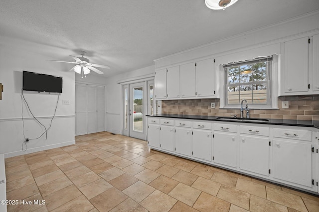 kitchen with white cabinetry, sink, decorative backsplash, and a textured ceiling