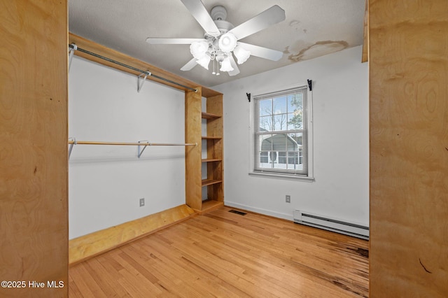 unfurnished bedroom with a baseboard heating unit, ceiling fan, and light hardwood / wood-style flooring