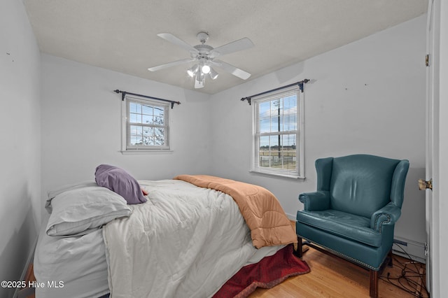 bedroom featuring baseboard heating, ceiling fan, and wood-type flooring