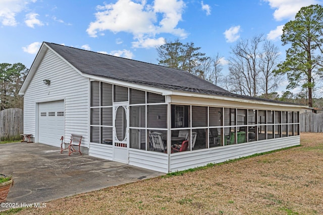 view of home's exterior with a garage, a sunroom, and a lawn