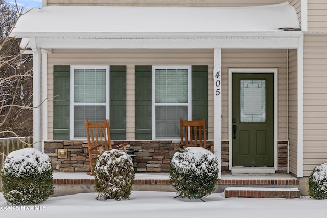 snow covered property entrance featuring a porch