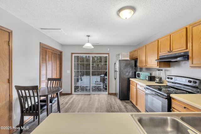 kitchen featuring sink, hardwood / wood-style flooring, black appliances, a textured ceiling, and decorative light fixtures