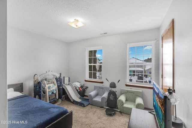 bedroom with light colored carpet and a textured ceiling