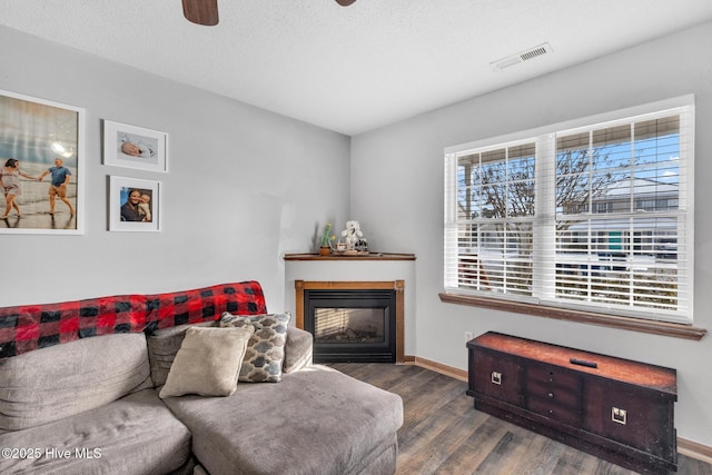 living room with ceiling fan, a textured ceiling, and dark hardwood / wood-style flooring