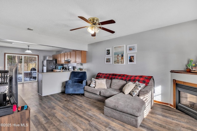 living room featuring ceiling fan, dark hardwood / wood-style floors, and a textured ceiling